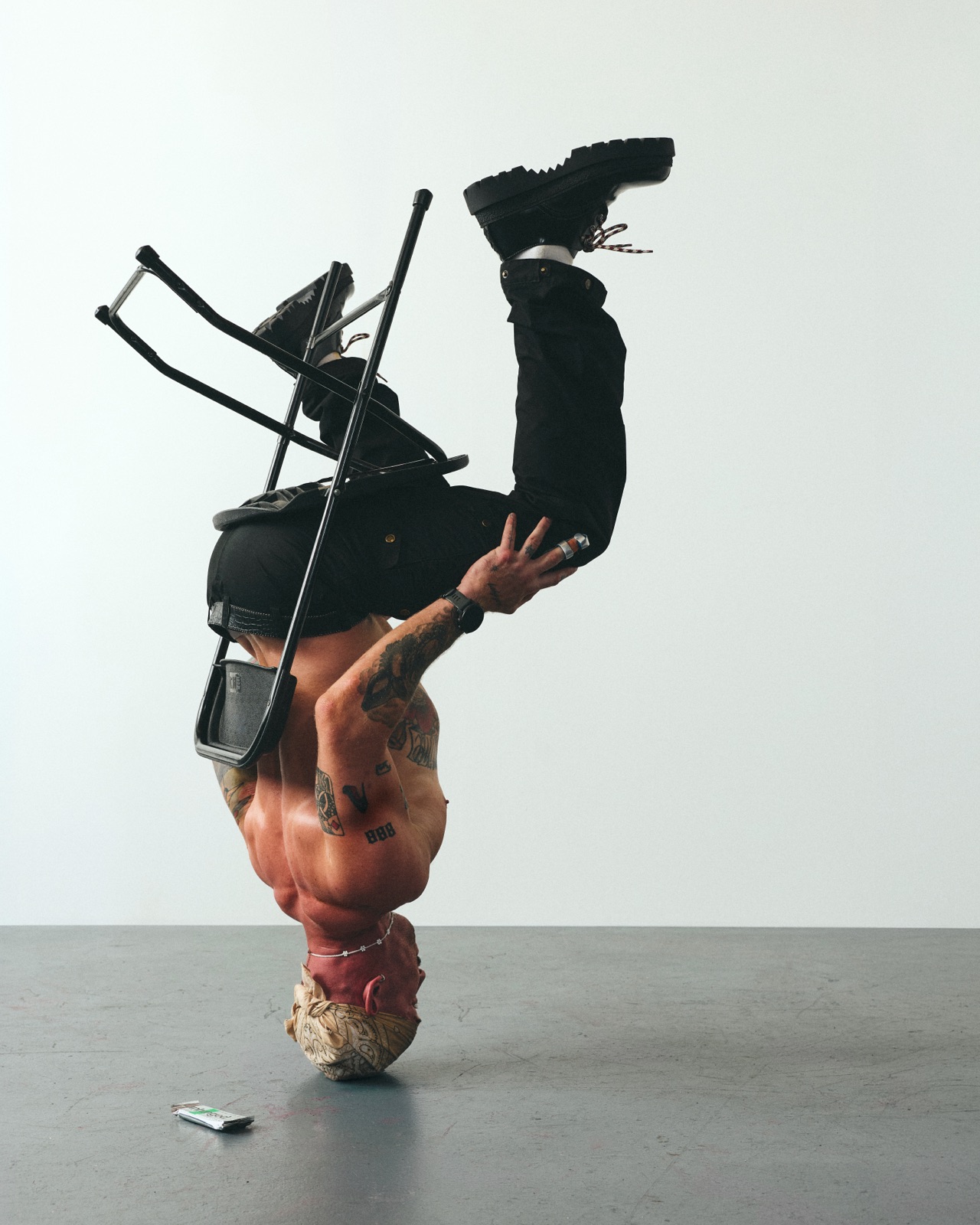 Austin balanced upside down on his head, a folding chair hooked over his legs