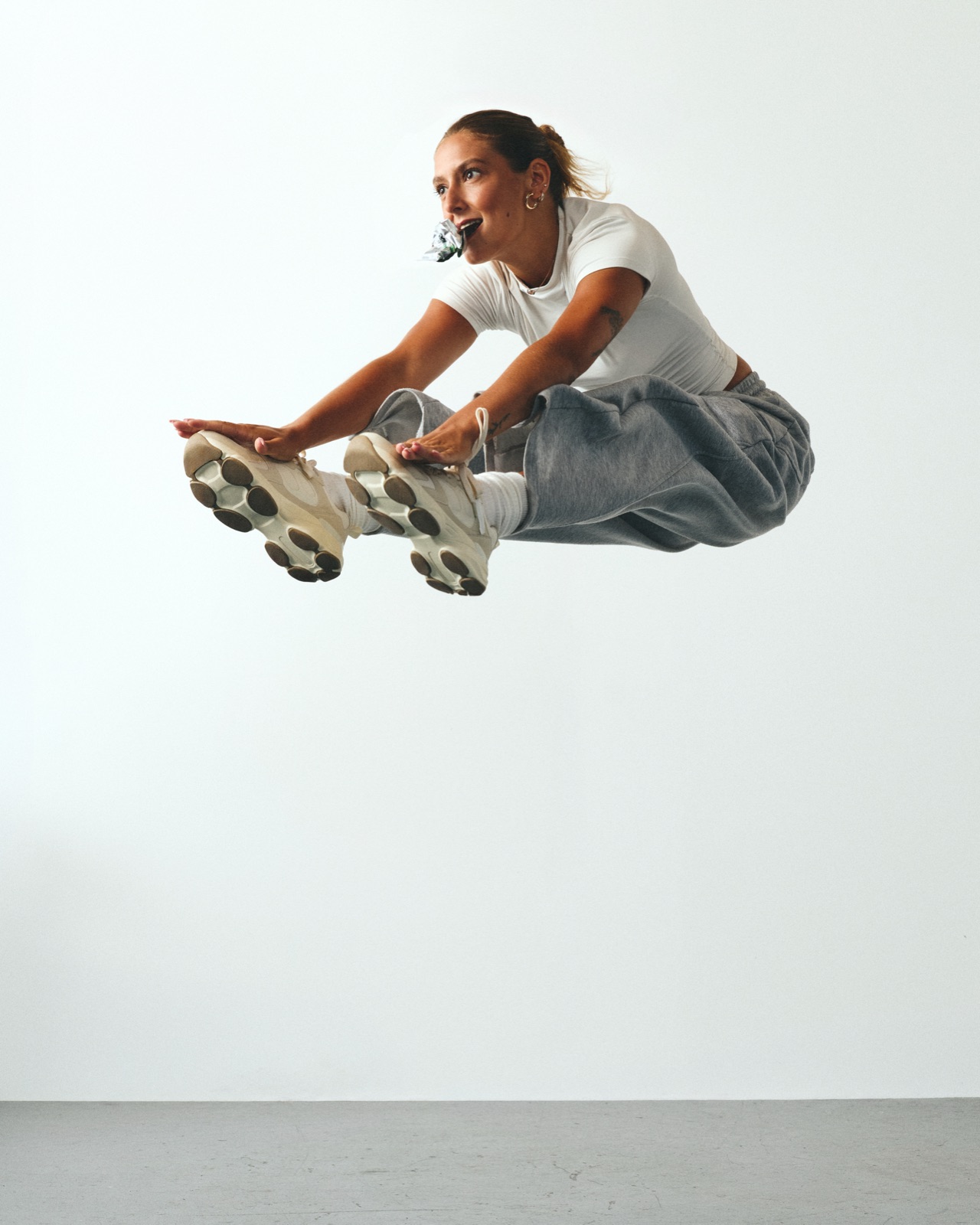 Reagan mid-air in a tucked jump, an Unhinged bar in her teeth